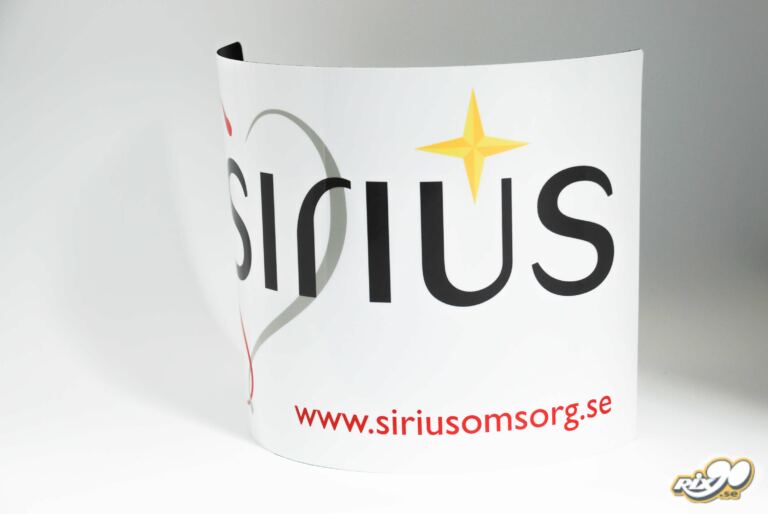 Böjd magnetskylt med Sirius Omsorgs logotyp på en bildörr