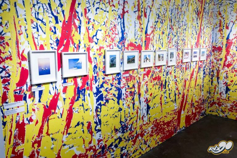 Väggdekor i rött, gult och blått bakom inramade fotografier på museum