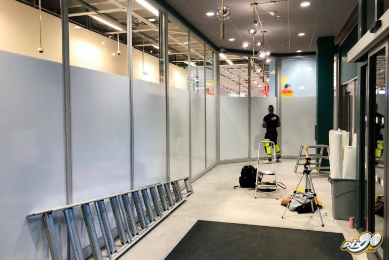 Täckning av insyn med vit dekorfilm på fönster som avskärmning vid byggnation i Stockholm