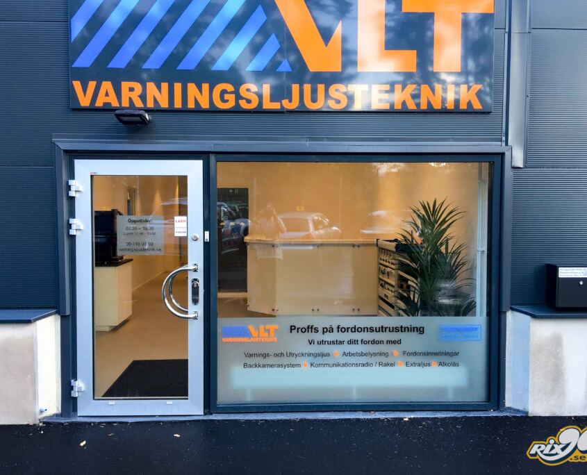Fasadskylt i aluminium ovanför entrén till VLT Varningsljusteknik i Stockholm