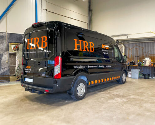 Bildekaler och varselrand på jourbil till HRB Riv & Sanering Orange logotyp, jourtext och varselrand på svart Mercedes-Benz Sprinter L3H2 jourbil till HRB Riv & Sanering