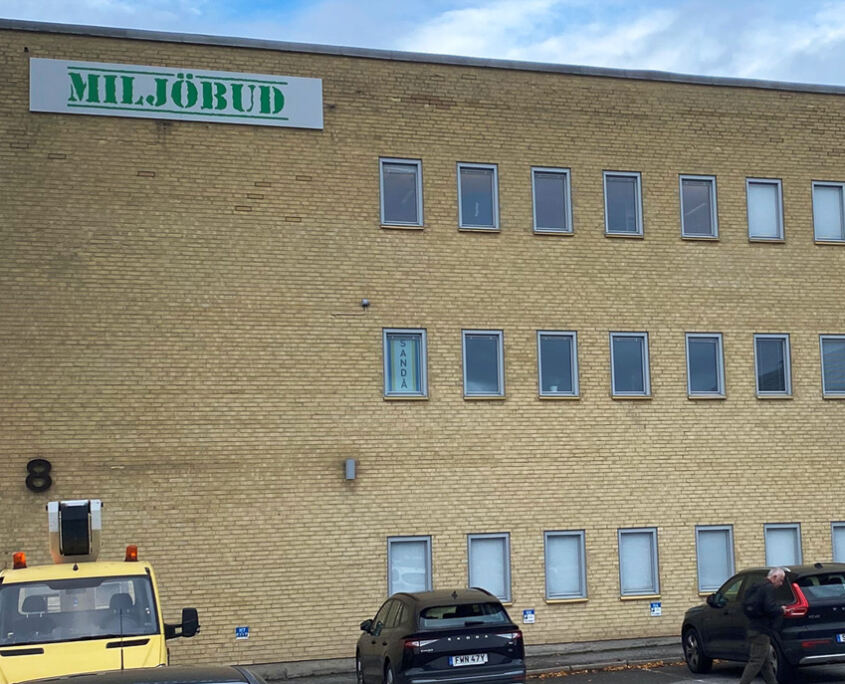 Kantvikt aluminiumskylt med grön logotyp på fasad till Miljöbud