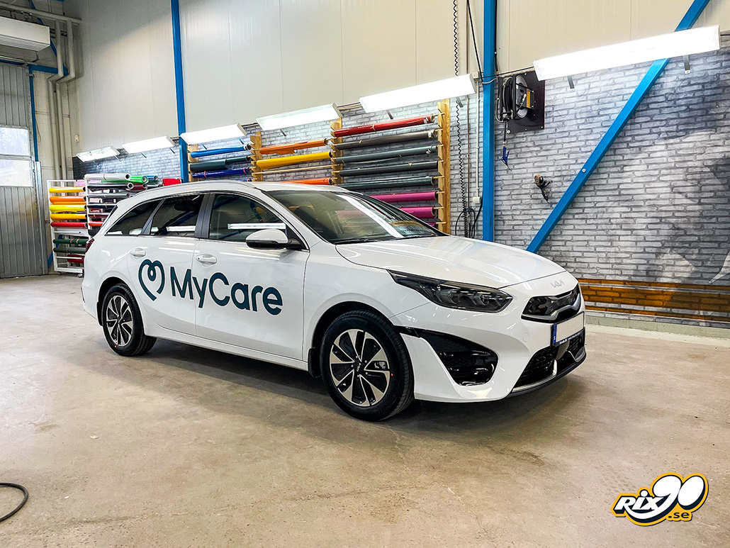 Bildekaler på dörrarna till tjänstebil Turkos logotyp på vit Kia Ceed kombi till MyCare, monterad i Rix90:s verkstad