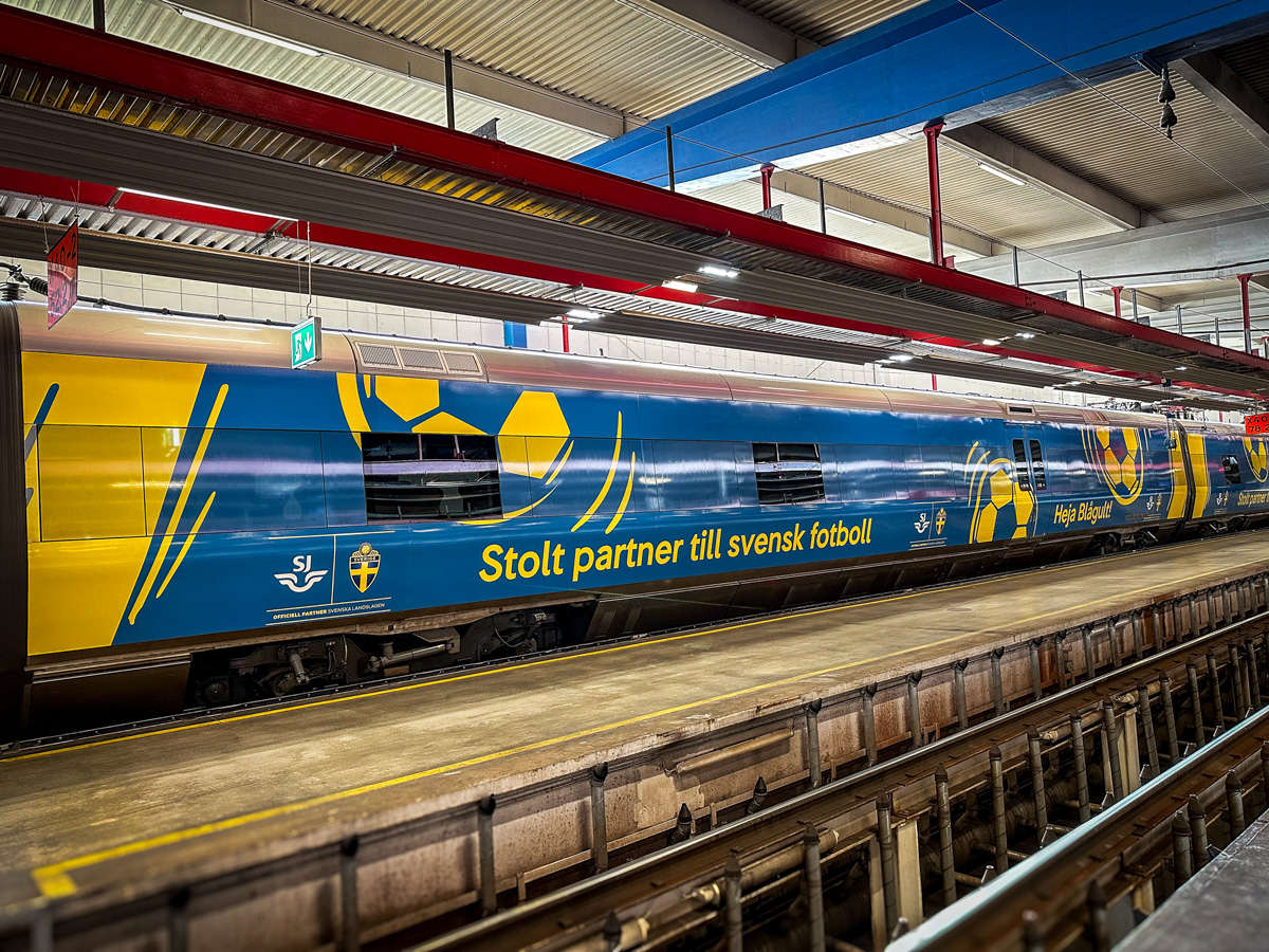Tågfoliering av SJ X55 för fotbolls-VM 2026 Helfolierad SJ-vagn i blått och gult med fotbollsmotiv och texten Stolt partner till svensk fotboll