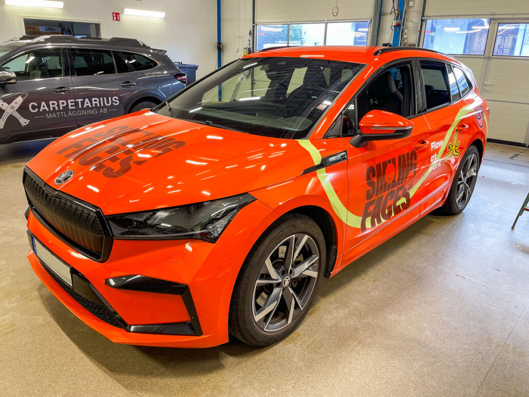 Helfolierad Skoda Enyaq i orange med grafik till Smiling Faces Helfolierad Skoda Enyaq i orange med grafik till Smiling Faces