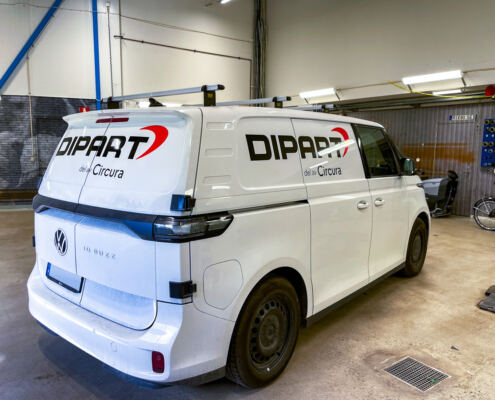 Bildekaler på VW ID. Buzz till Dipart Svart logotyp med röd båge och texten del av Circura på vit VW ID. Buzz till Dipart