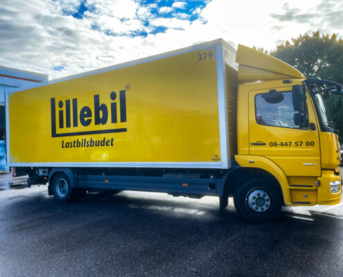 Fordonsdekor på lastbil till Lillebil Lastbilsbudet Fordonsdekor på gul Mercedes-Benz Atego med logotyp och telefonnummer till Lillebil Lastbilsbudet