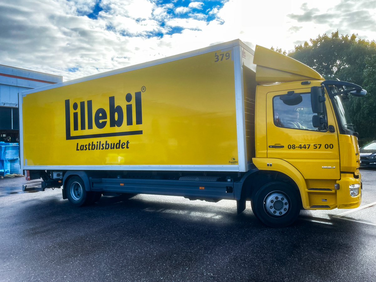 Fordonsdekor på lastbil till Lillebil Lastbilsbudet Fordonsdekor på gul Mercedes-Benz Atego med logotyp och telefonnummer till Lillebil Lastbilsbudet