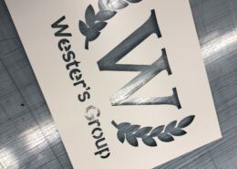 Schablon i plast med logotyp Skuren schablon i plast med logotyp, lagerkrans och text, liggande på skärbordet