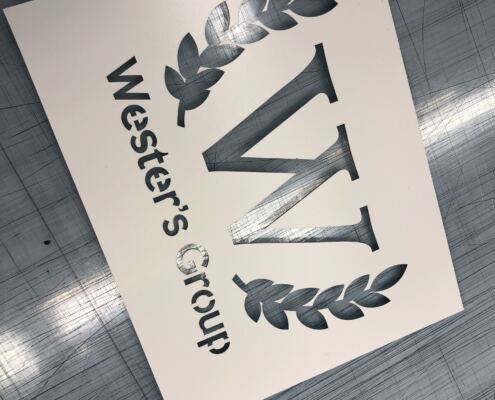Schablon i plast med logotyp Skuren schablon i plast med logotyp, lagerkrans och text, liggande på skärbordet